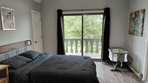 A bedroom with a bed, a dresser, a window with curtains, and a balcony. - Spacious 6 bedroom, 5 bathroom, and 2 game room house on Grand Lake! (Saint Marys)