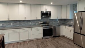 A modern kitchen with white cabinets, a stainless steel refrigerator, a microwave, and a dishwasher. - Spacious 6 bedroom, 5 bathroom, and 2 game room house on Grand Lake! (Saint Marys)