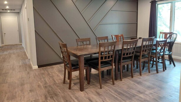 A dining area with a large table and multiple chairs, a modern wall design, and a window with curtains. - Spacious 6 bedroom, 5 bathroom, and 2 game room house on Grand Lake! (Saint Marys)