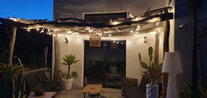 An outdoor patio with string lights, wooden furniture, and potted plants. - Beautiful, air-conditioned house with a hot tub (Calvisson)