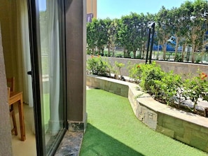 A balcony with a view of a landscaped garden, a wooden chair, and a glass door.