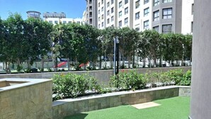 A courtyard with artificial grass, stone planters, and a building in the background.