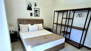 A bedroom with a bed, nightstands, a wardrobe, and framed pictures on the wall.