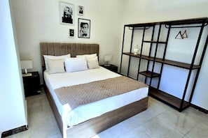 A bedroom with a bed, nightstands, a wardrobe, and framed pictures on the wall.