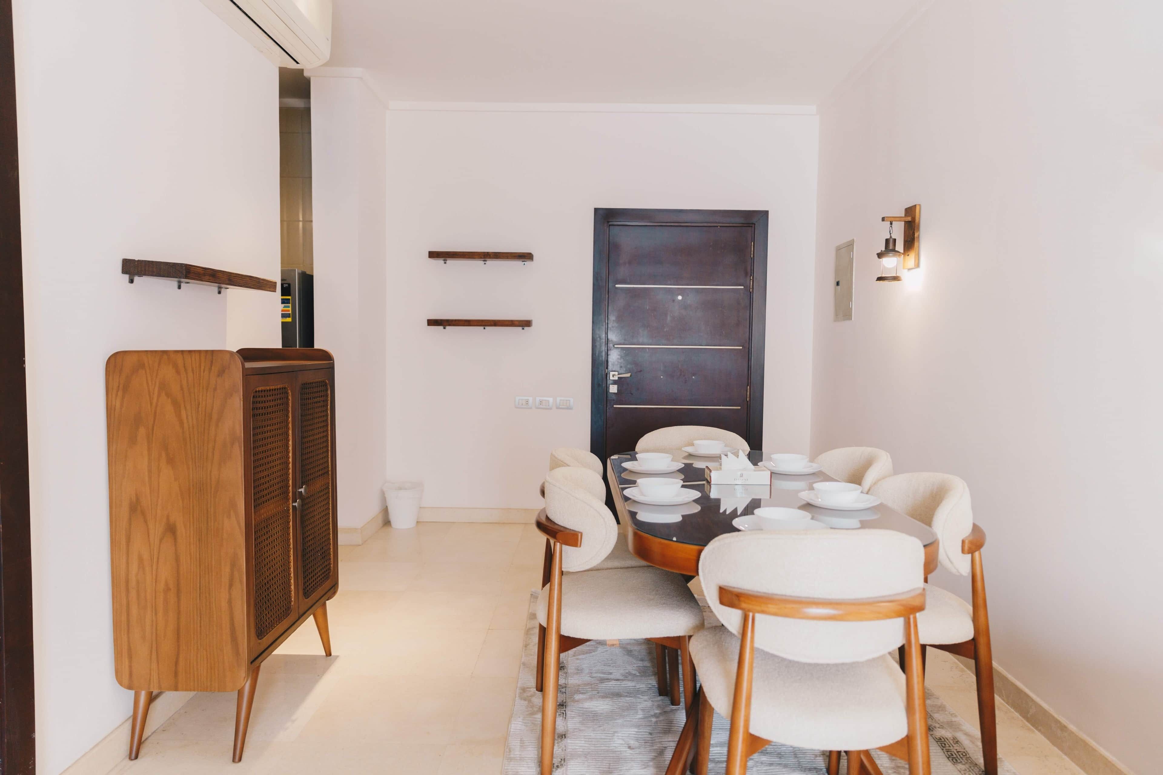 A dining area with a round table, chairs, a cabinet, and a door.
