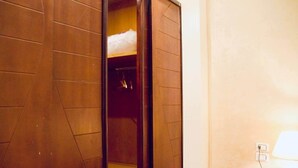 Ein Hotelzimmer mit Holzschrank, Nachttisch mit Lampe und einer Steckdose.