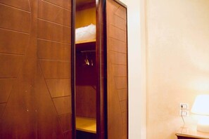 A hotel room with a wooden wardrobe, a bedside table with a lamp, and a wall socket. - Maple and Moon Suite - Comfort & Elegance Stay 5 (New Cairo City)