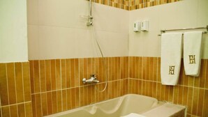 Ein Badezimmer mit einer Badewanne, einer Dusche und zwei Handtüchern, die an einem Haken hängen.
