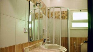 Ein Badezimmer mit Marmorwaschbecken, einer Glasdusche und einem Spiegel.