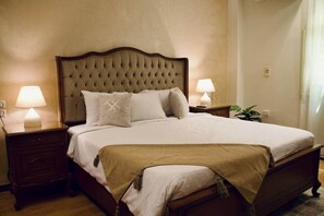 A neatly made bed with a tufted headboard, two bedside tables with lamps, and a small plant on the right side. - Maple and Moon Suite - Comfort & Elegance Stay 5 (New Cairo City)