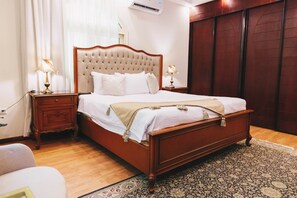 A bedroom with a wooden bed, two bedside tables with lamps, a patterned rug, and a wooden wardrobe. - Maple and Moon Suite - Comfort & Elegance Stay 1 (New Cairo City)