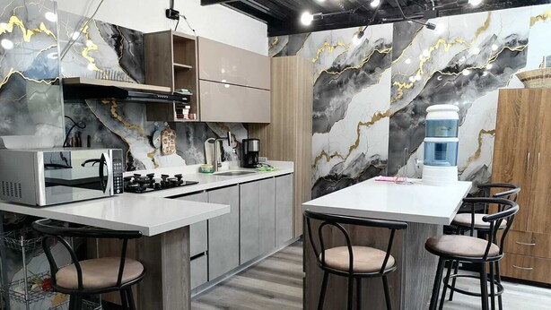 A modern kitchen with a marble backsplash, stainless steel appliances, and bar stools.