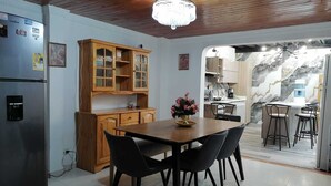 A kitchen with wooden cabinets, a dining table with chairs, a refrigerator, and a chandelier.