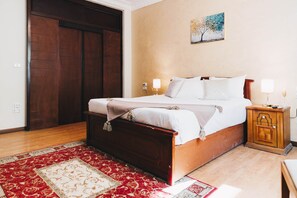 A bedroom with a wooden bed, a nightstand, a wall-mounted lamp, and a door. - Maple and Moon Suite - Comfort & Elegance Stay 3 (New Cairo City)
