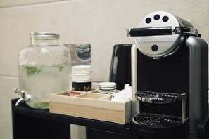 Eine Kaffeestation mit einer Nespresso-Maschine, einem Wasserspender und einem Glasbehälter mit Wasser.