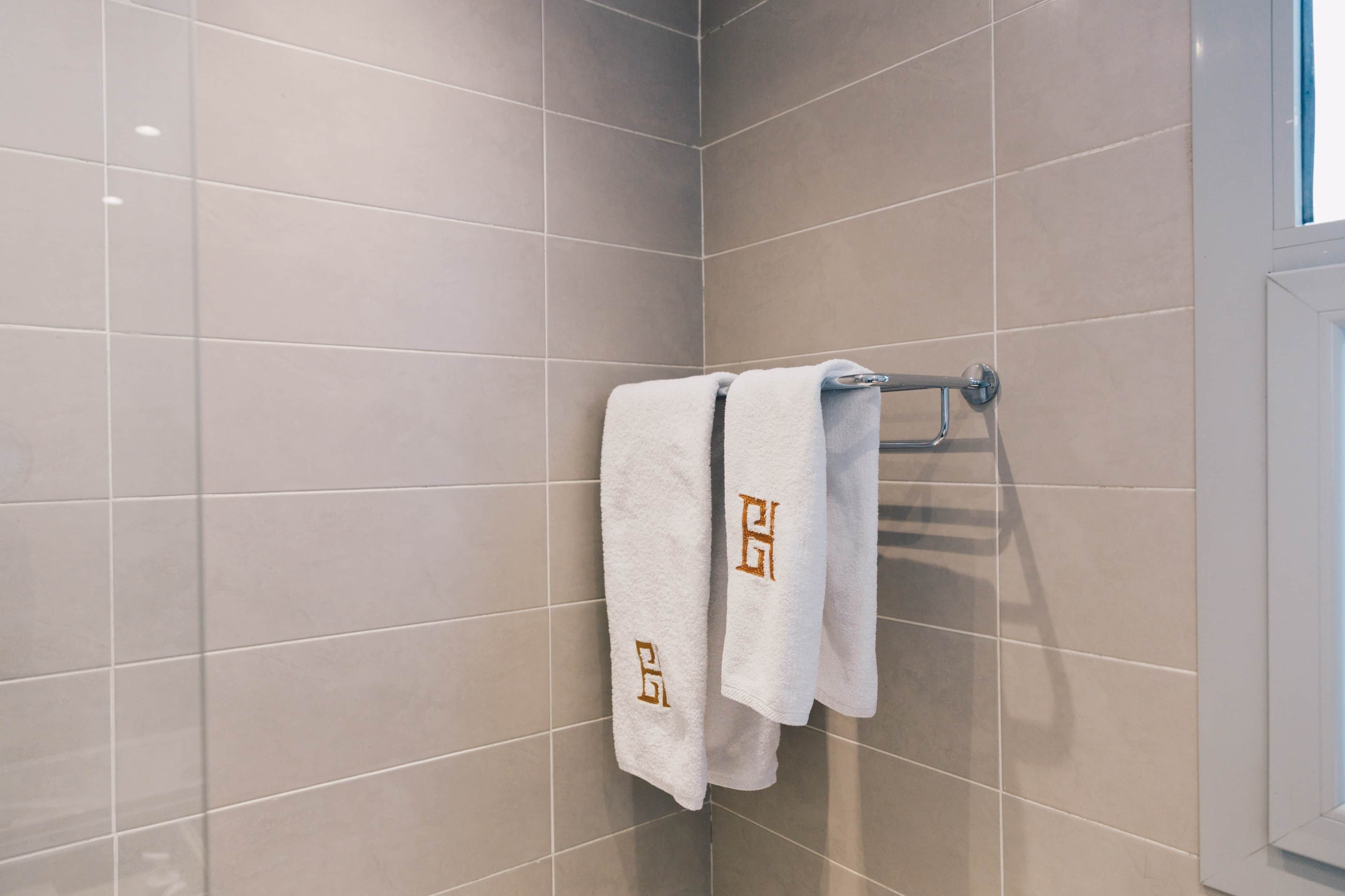 Une salle de bain avec un mur carrelé, un porte-serviettes avec deux serviettes et une porte.