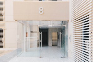 Entrada de um edifício com porta de vidro, placa com o número 8 e portão de metal.