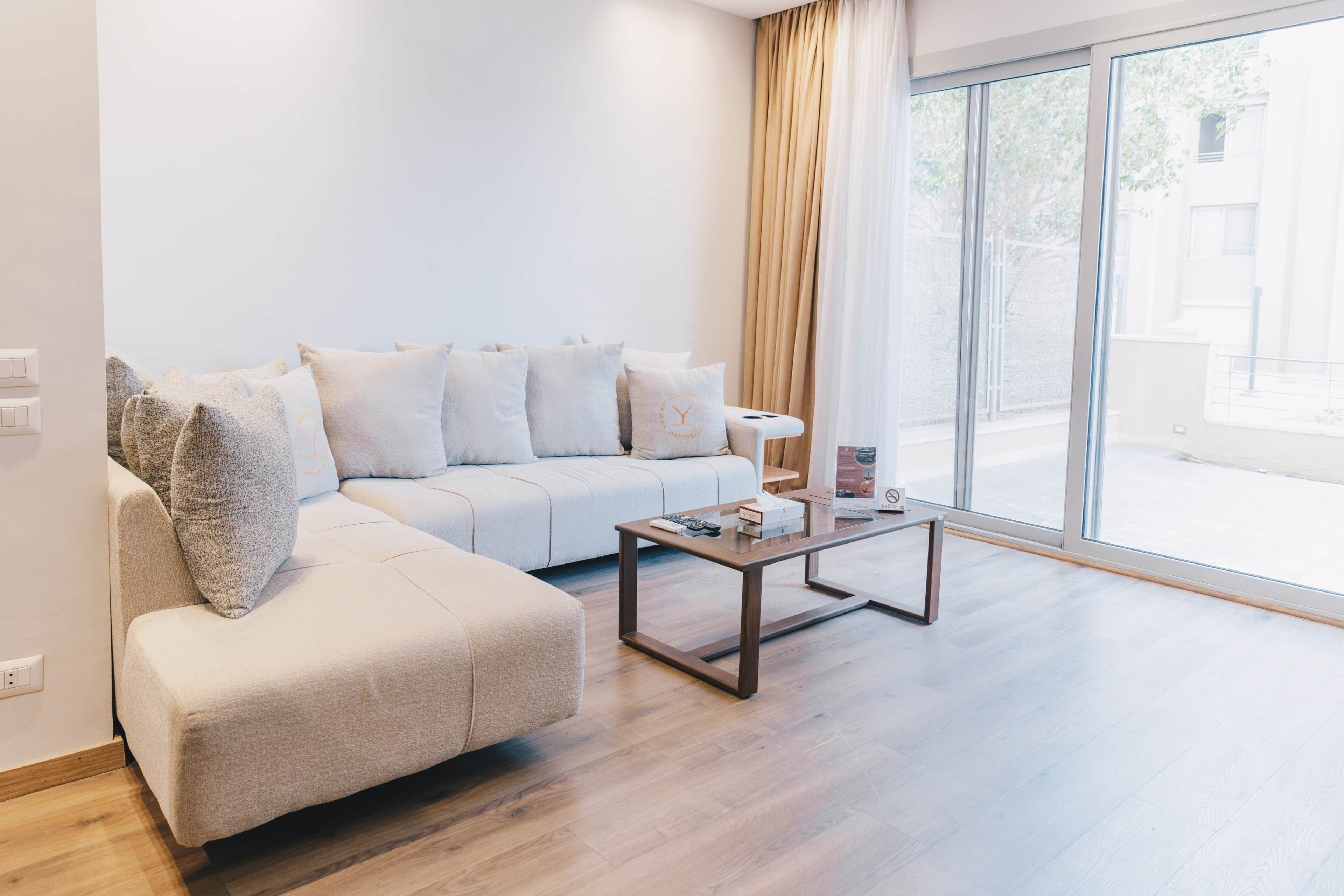Uma sala de estar moderna com um sofá, uma mesa de centro e uma grande janela com cortinas.