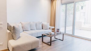 Ein modernes Wohnzimmer mit einer Couch, einem Couchtisch und einem großen Fenster mit Vorhängen.