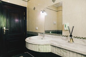 A bathroom with a marble sink, a mirror, a door, and a hand sanitizer dispenser. - Maple and Moon Suite - Comfort & Elegance Stay 4 (New Cairo City)