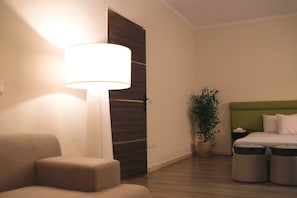 Ein Hotelzimmer mit einem Bett, einem Nachttisch, einer Lampe, einem Sessel und einer Zimmerpflanze.