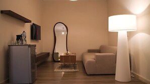 Een moderne woonkamer met een bank, een lamp, een spiegel en een kleine tafel.