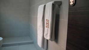 Een badkamer met een douche, toilet en twee handdoeken die aan een rek hangen.