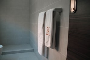 A bathroom with a shower, a toilet, and two towels hanging on a rack. - VIOLA Brand New Studio - 44 (New Cairo City)