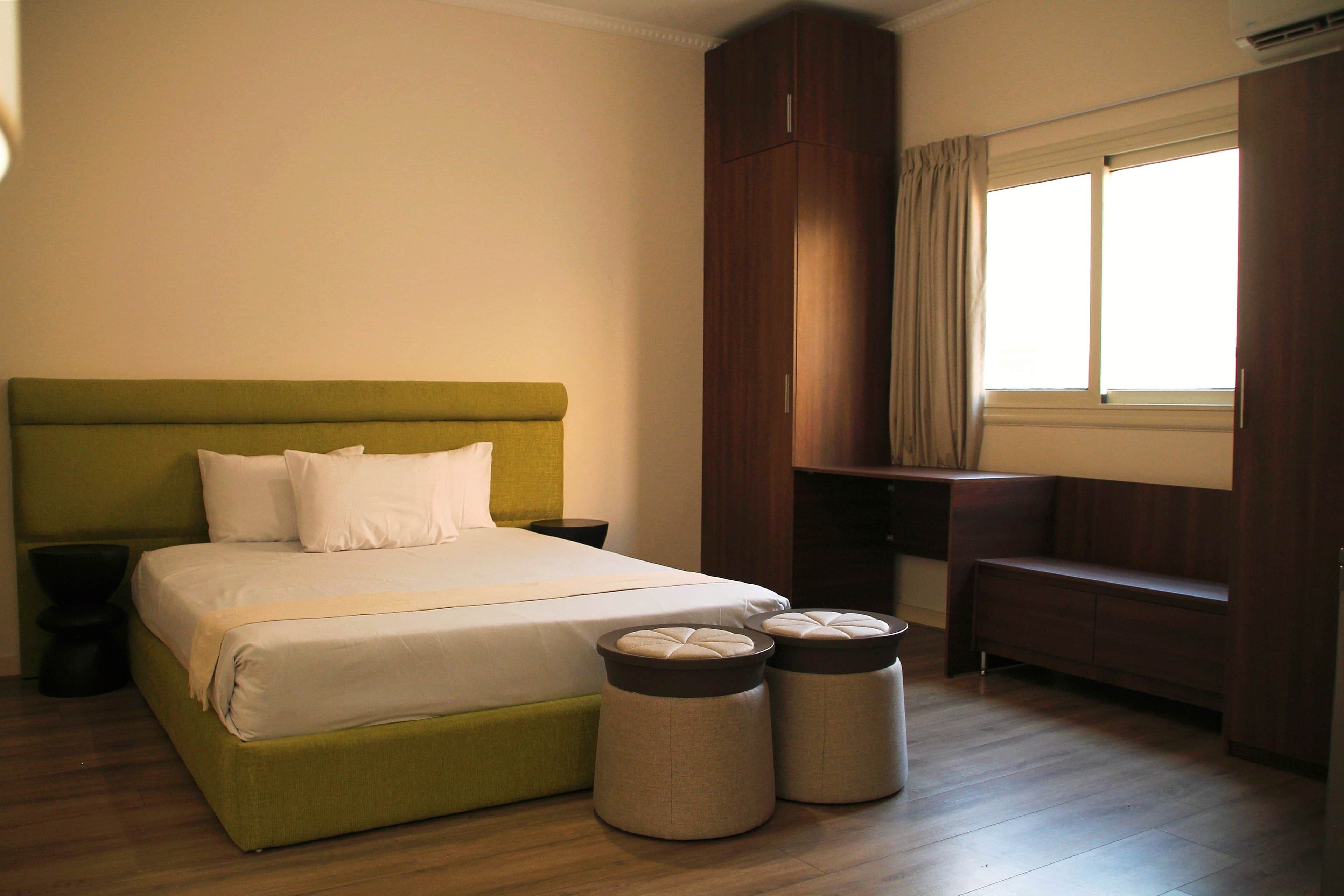 A bedroom with a bed, bedside tables, a bench, and a wardrobe.