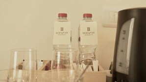 Una camera d'albergo con due bottiglie etichettate 'Elegant Hospitality' e una macchina per il caffè espresso nera.
