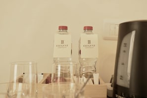 Ein Hotelzimmer mit zwei Flaschen mit dem Aufdruck 'Elegant Hospitality' und einer schwarzen Kaffeemaschine.