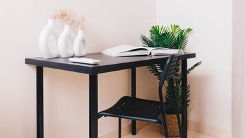 A desk with three white vases, an open book, and a potted plant.