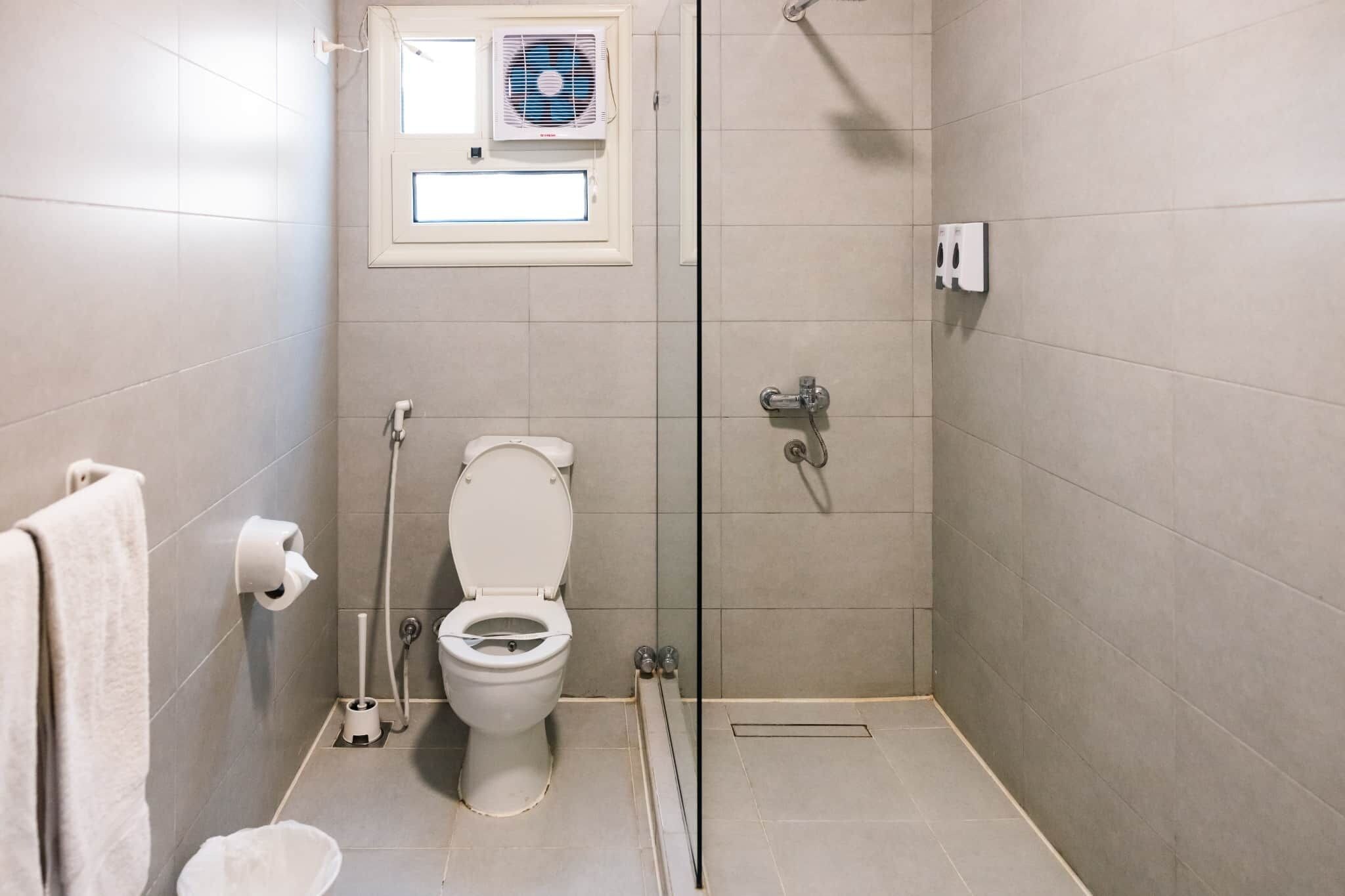 Ein kleines, modernes Badezimmer mit Toilette, Dusche und Handtuchhalter.