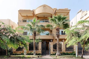 A multi-story building with balconies, palm trees, and a gated entrance. - Maple and Moon Suite - Comfort & Elegance Stay 6 (New Cairo City)