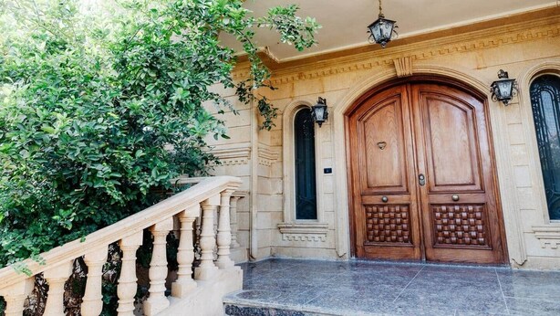 A grand entrance with a wooden door, a stone staircase, and a decorative railing. - Maple and Moon Suite - Comfort & Elegance Stay 6 (New Cairo City)