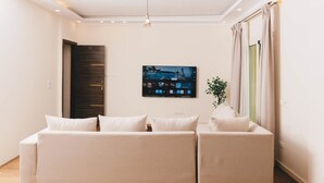 Una sala moderna con un sofá, un televisor de pantalla plana y una planta.