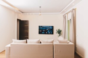 A modern living room with a sofa, a flat-screen TV, and a plant. - VIOLA Near Waterway  - 42 (New Cairo City)