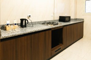 A kitchen with a granite countertop, a black stove, a microwave, and a coffee maker. - VIOLA Near Waterway  - 42 (New Cairo City)
