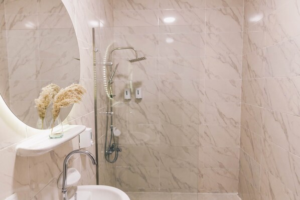 A modern bathroom with a marble floor, a glass shower enclosure, a white sink, and a vase with dried flowers. - VIOLA Near Waterway  - 01 (New Cairo City)