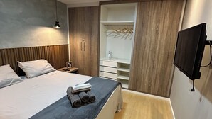 Un dormitorio moderno con cama, mesita de noche y vestidor con espejo.