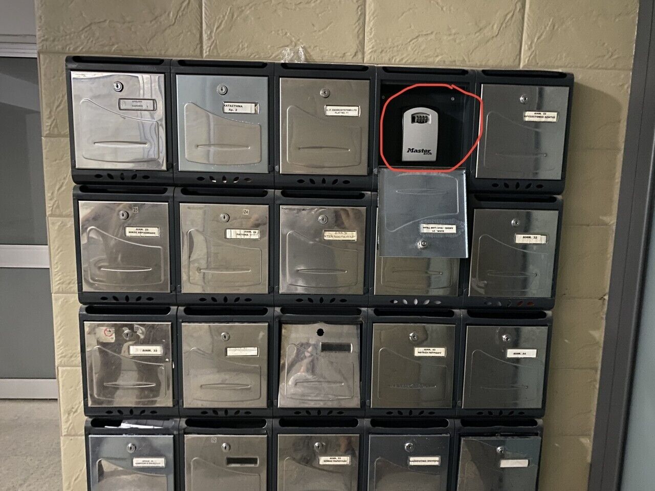 Un mur composé de boîtes de rangement en métal, chacune portant une étiquette, et l’une d’entre elles est mise en évidence par un cercle rouge.