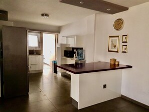 A modern kitchen with a marble countertop, a refrigerator, a microwave, and a clock on the wall. - Central Luxurious 2 bedroom flat (Nicosia)