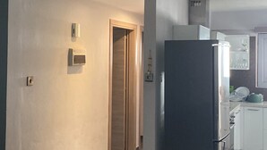 Eine moderne Küche mit einem großen Kühlschrank, einer Holztür und einem Fliesenboden.