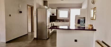 Una cocina moderna con una isla central, electrodomésticos de acero inoxidable y un amplio ventanal que proporciona luz natural.