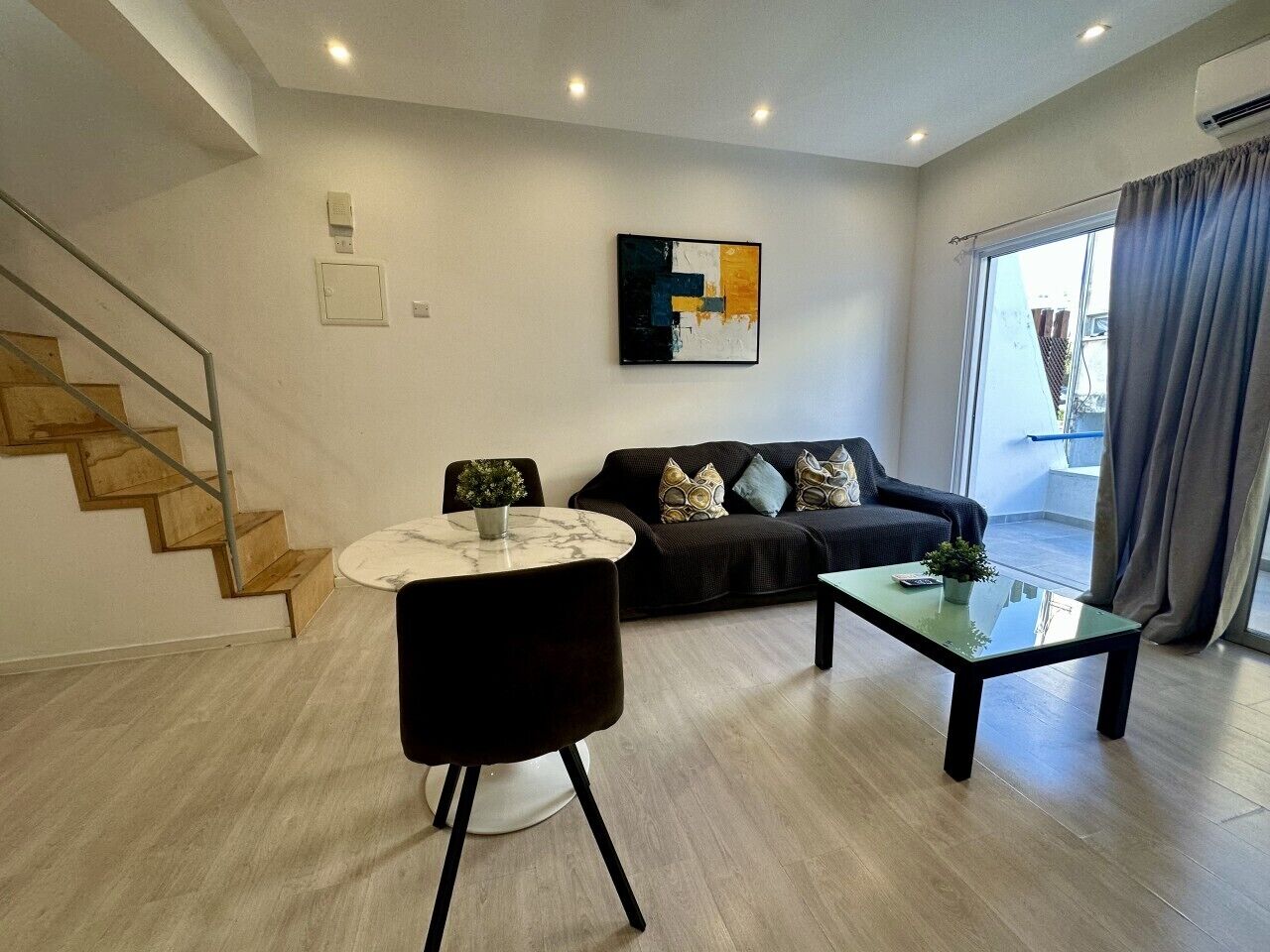 Ein modernes Wohnzimmer mit Treppe, Sofa, Couchtisch und Esstisch.