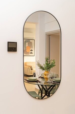 Une pièce comprenant une table à manger, des chaises, un vase avec des fleurs et une œuvre d’art encadrée accrochée au mur.