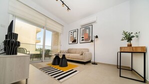 Ett modernt vardagsrum med en soffa, ett soffbord, en golvlampa och ett sidobord med en växt.