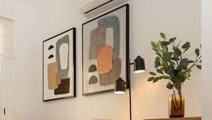 Ett modernt vardagsrum med en soffa, abstrakta målningar, en golvlampa och en krukväxt.