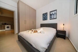 Une chambre à coucher comprenant un lit, une table de chevet, une lampe, une armoire et un coin cuisine.