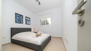 Ett sovrum med en säng, ett fönster, en dörr och en lampa.